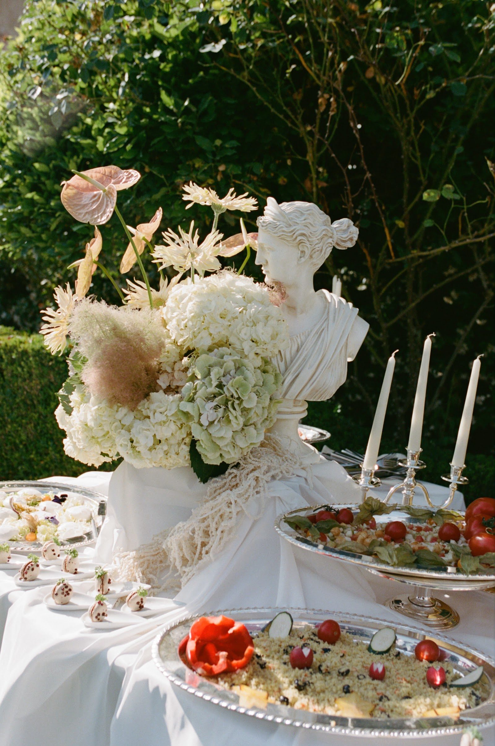 Hochzeitstafel mit Blumenarrangement und Statue